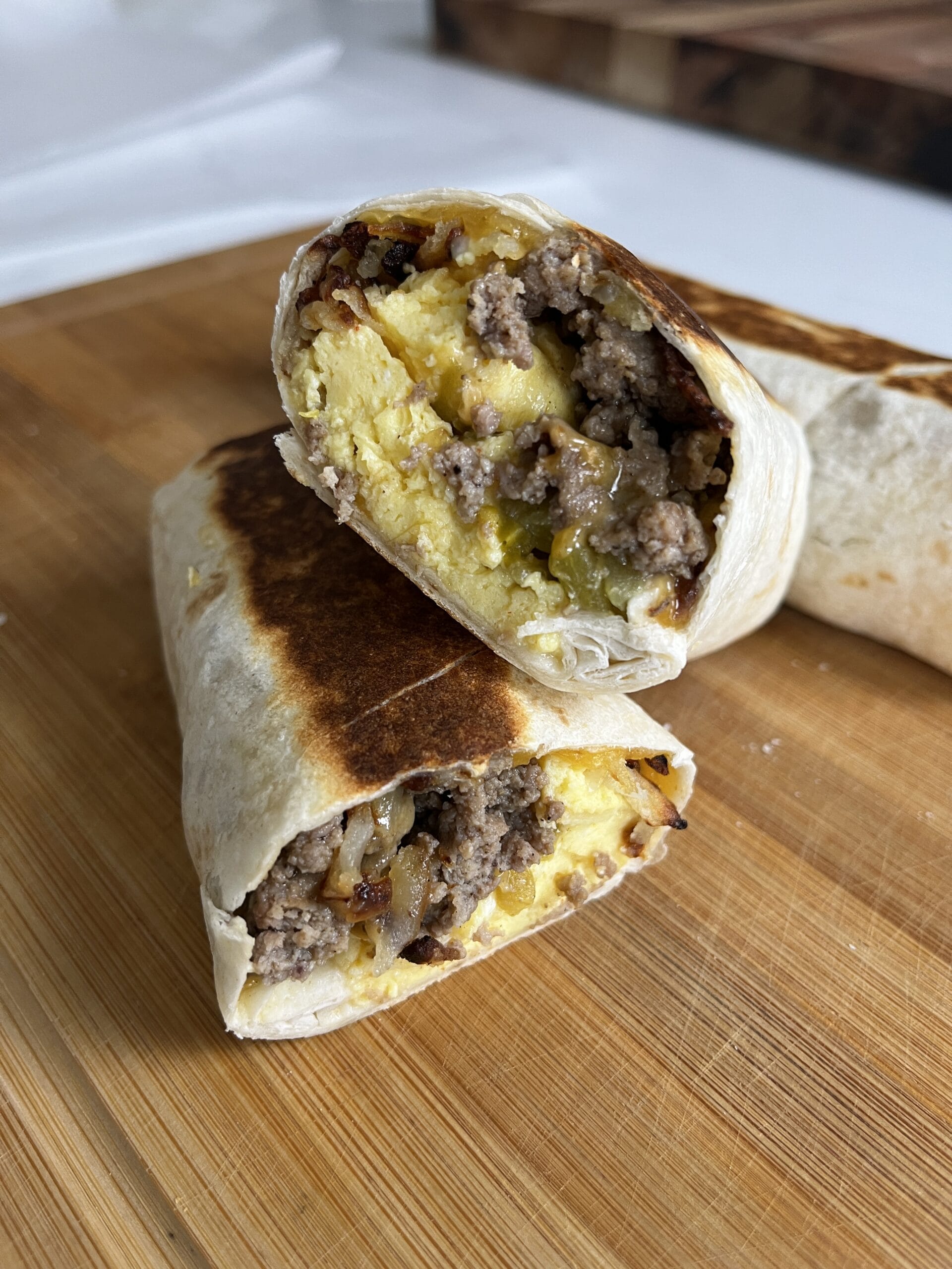 Breakfast burrito cut in half on a cutting board.