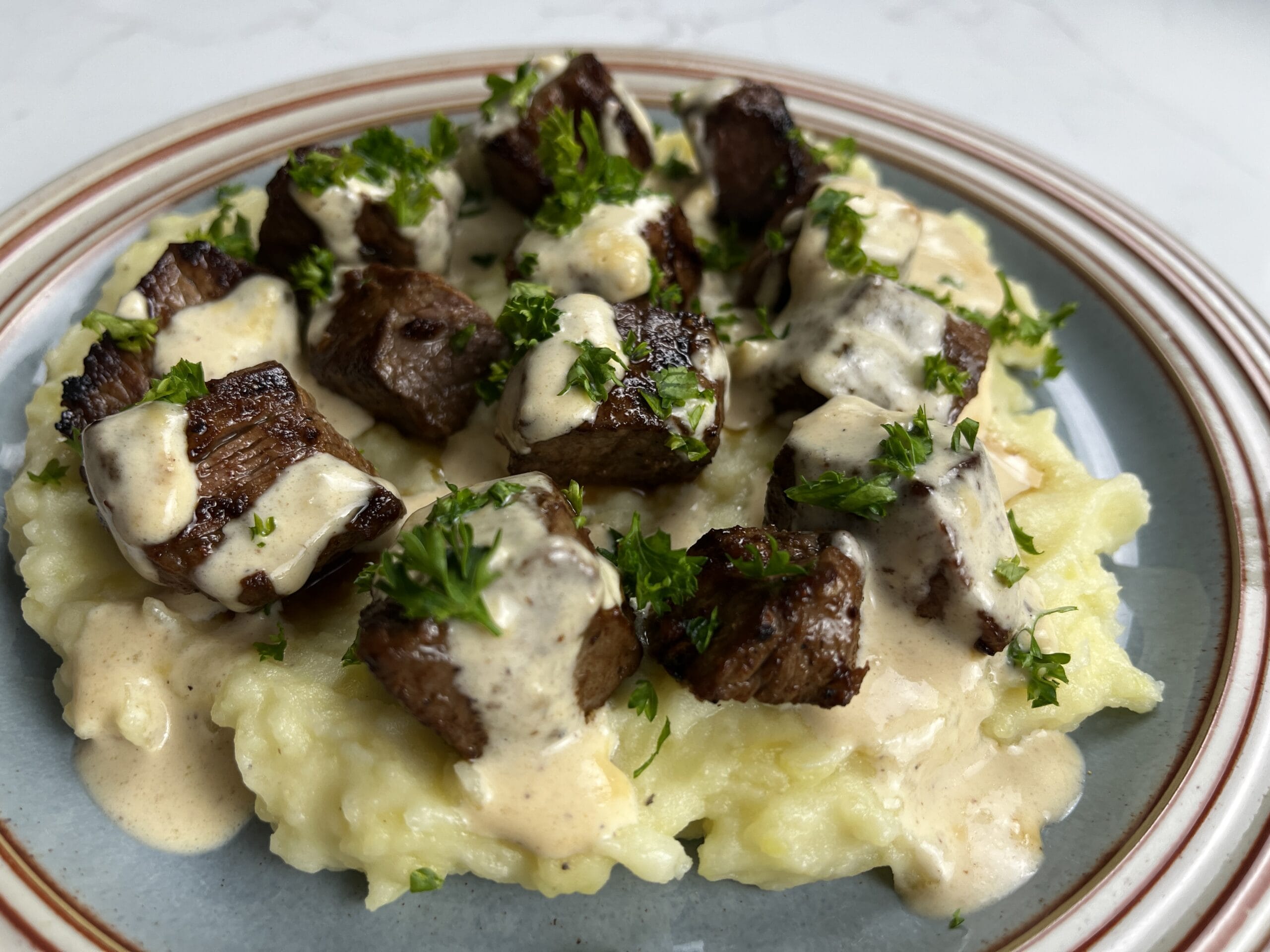 Garlic Butter Steak Bites with Creamy Parmesan Sauce over Garlic Mashed Potatoes