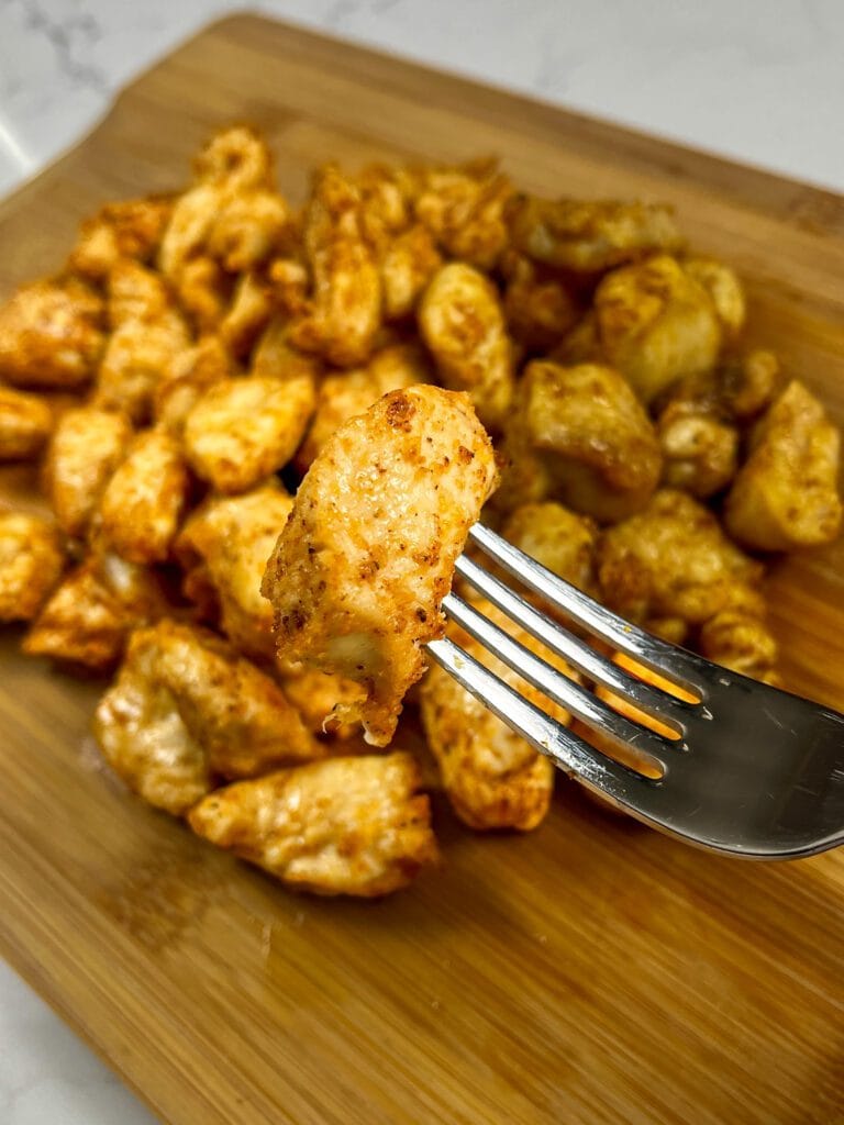 A fork with a bite of air fried crispy parmesan chicken.